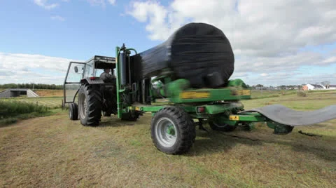 Tractor wrapping bail of hay Stock Footage 22900177