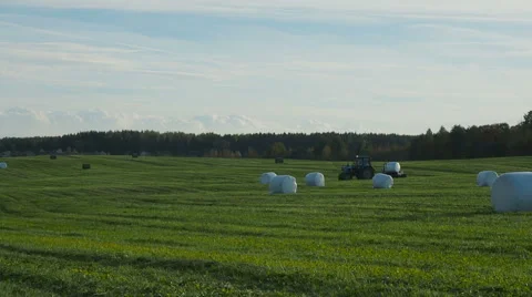Tractor wrapping a bale of hay after collecting the dried hay on a field Stock Footage 68189837