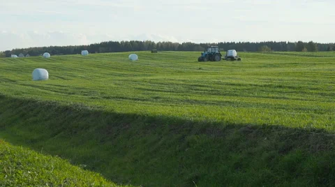 Tractor wrapping a bale of hay after collecting the dried hay on a field Stock Footage 68189914