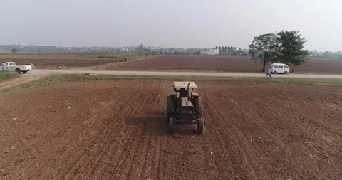 Tractors plough fields in spring.   A tractor with disc harrows ploughs footage. Stock Footage 291678691