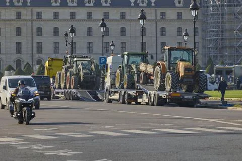 Tractors on trailers driving through Paris city street 库存照片