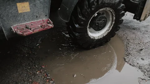 A tractors wheels with driving through mud and puddles at a construction site. Video stock 318268423