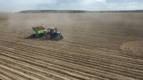 Tractors at work in a field cultivating the soil ready for potatoes to be plante Stock Footage 128733342