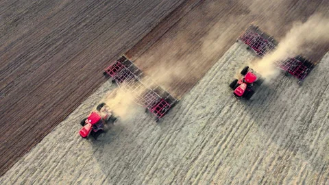 Tractos plowing ground preparing soil for palnting seeds. Agriculture farm Stock Footage 196731054