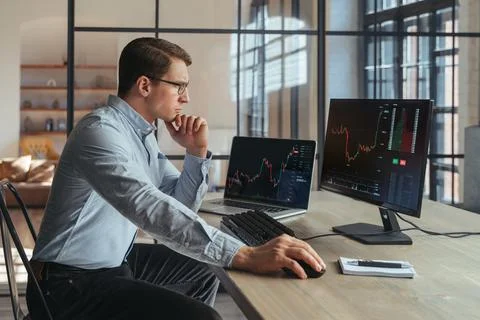Trader analyst at office analyzing indexes, financial chart, trading online at Stock Photos