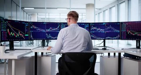 Trader Analyzing Stock Data On Multiple Computer Monitors In Office Stock Photos