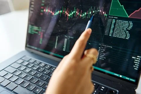 Trader analyzing stock market data on laptop screen Stock Photos