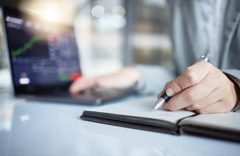 Trader, hands and writing notes in book by laptop on stock market chart or graph Stock Photos