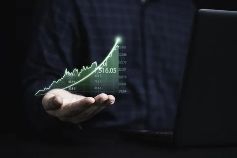 Trader holding green graph chart with arrow and using laptop computer for a.. Stock Photos