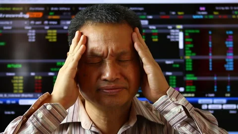 Trader  holding   head with hand  , blurred stock exchange board background. Stock Footage 151889786