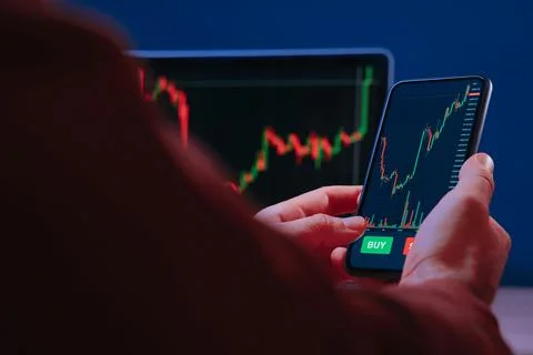 Trader holding smartphone, using trading app for analyzing stock market Stock Photos
