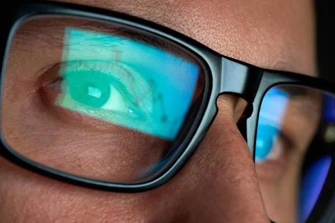 Trader looking at computer screen analyzing trading chart reflecting in glasses. Stockfoto's