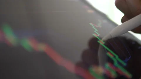 Trader use pen trade forex maket stock on mobile with candle stick chart Stock Footage 167013981
