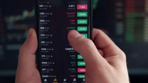 Trader using smartphone checking stock exchange, investing app Online Stock Footage 236454011