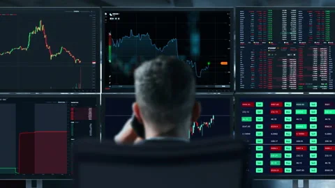 Trader is working with multiple computer screens full of charts and data Stock Footage 153105818