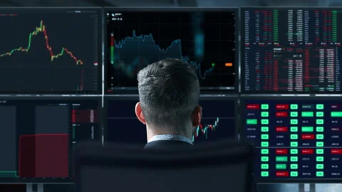 Trader is working with multiple computer screens full of charts and data Stock Footage 153667211