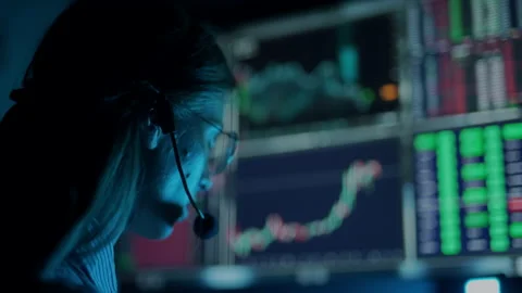 Trader is working with multiple computer screens with charts and data analysis Stock Footage 156702372