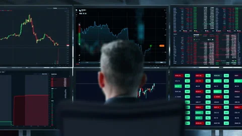 Trader is working with multiple computer screens full of charts and data Stock Footage 157583676