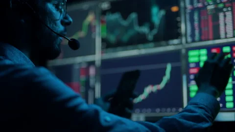 Trader is working with multiple computer screens with charts and data analysis Stock Footage 164552484