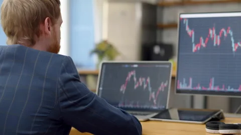 Trader working with multiple computer screens full of charts and data analysis Stock Footage 165722358
