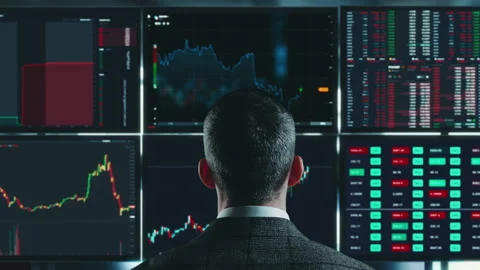 Trader is working with multiple computer screens full of charts and data Stock Footage 188256169