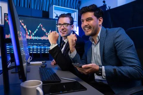 Traders comparing dynamic investment graph via phone and pc. Sellable. Stock Photos