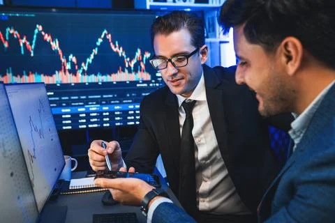 Traders comparing dynamic investment graph via phone and pc. Sellable. Stock Photos