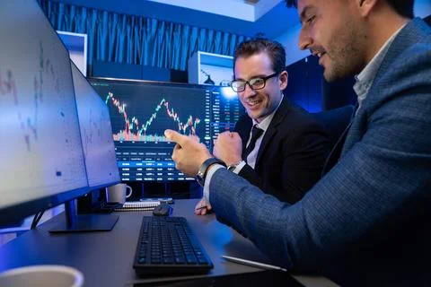 Traders comparing dynamic investment graph via phone and pc. Sellable. Stock Photos