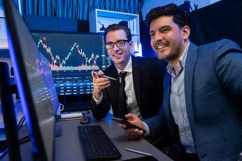 Traders comparing dynamic investment graph via phone and pc. Sellable. Stock Photos