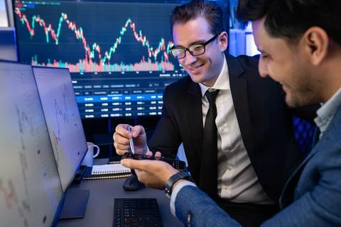Traders comparing dynamic investment graph via phone and pc. Sellable. Stock Photos