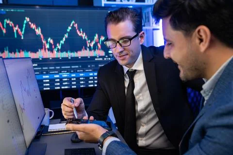 Traders comparing dynamic investment graph via phone and pc. Sellable. Stock Photos