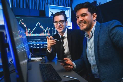 Traders comparing dynamic investment graph via phone and pc. Sellable. Stock Photos