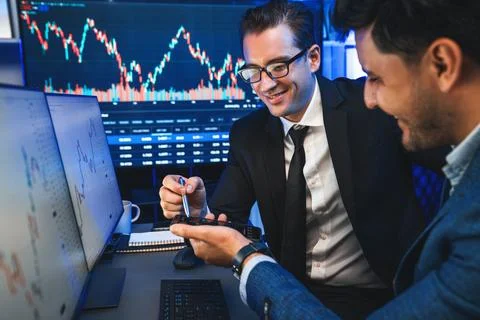 Traders comparing dynamic investment graph via phone and pc. Sellable. Stock Photos