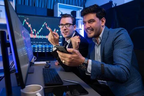 Traders comparing dynamic investment graph via phone and pc. Sellable. Stock Photos