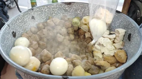 Trader's hand putting dumplings into plastic. Siomay seller at street food stall Stock Footage 280281689