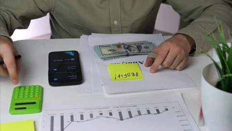 A traders hands handle cash marked profit while analyzing IPO documentation and 스톡 동영상 316458882