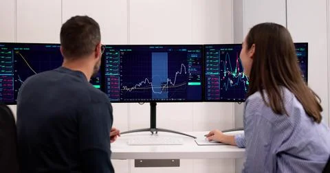 Trading Online On Multiple Computer Monitors In Office For Trades Stock Photos