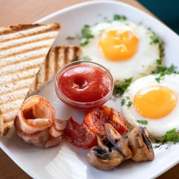 Traditional American continental breakfast. Fried eggs with bacon, mushrooms and Stock Photos