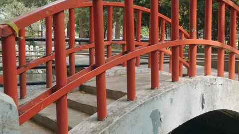Traditional arched red bridge in a public park setting. 库存影片 343369582