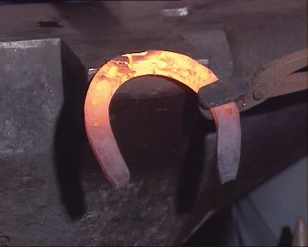 Traditional blacksmith hammering out the toe clip of a hot horseshoe Stock Footage 43822334