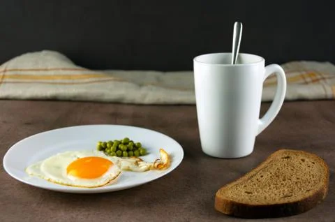 Traditional breakfast, fried eggs, bread, coffee in a white cup on a dark bac Stock Photos