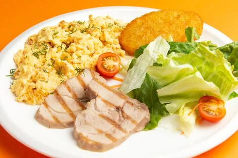 Traditional breakfast. Fried eggs, meat and hash brown in a plate. Stock Photos