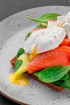 Traditional breakfast toast with salmon, poached egg and spinach on white plate Stock Photos