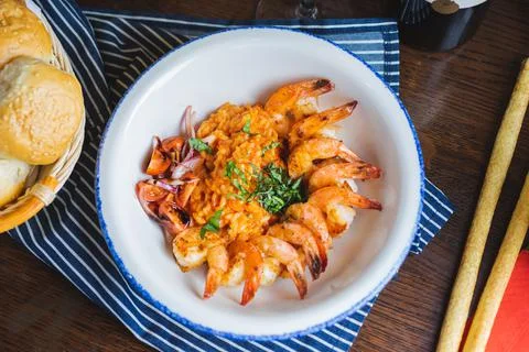 Traditional bright shrimp risotto in a bowl on a table in a restaurant with a Stock Photos