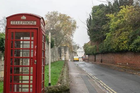 Traditional British red phone booth on street by the ancient wall of York Stock Photos