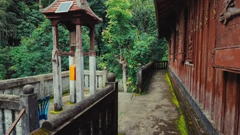Traditional Buddhist temple bell tower beside historic wooden monastery in Stock Footage 346225826