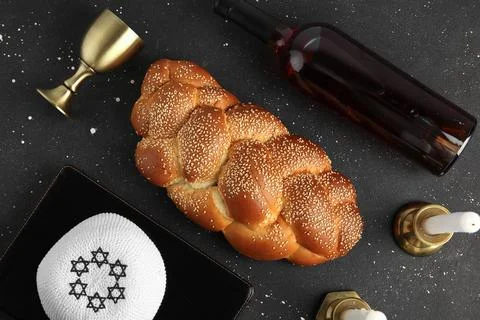 Traditional challah bread with goblet, wine and Jewish hat on dark background Stock Photos