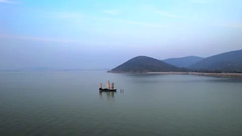 A traditional chinese junk boat sailing on a calm lake with mountains Video stock 341908562