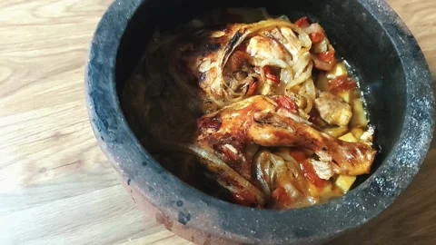 A traditional clay pot featuring roasted chicken legs with caramelized onions 動画素材 333240700