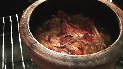 A traditional clay pot featuring roasted chicken legs with caramelized onions Stock Footage 333240706